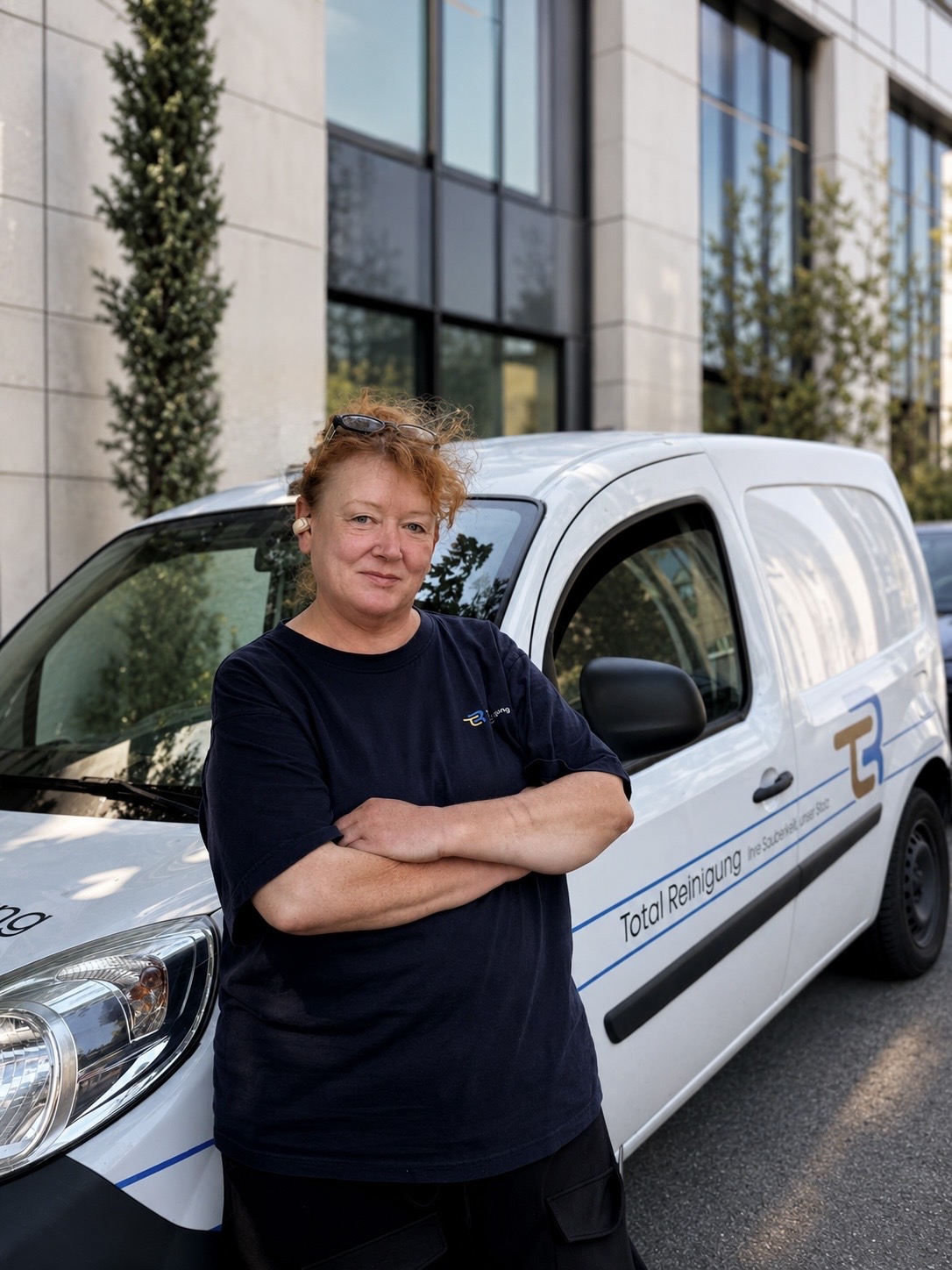 Mitarbeiterin der Total Reinigung GmbH vor dem Firmenfahrzeug