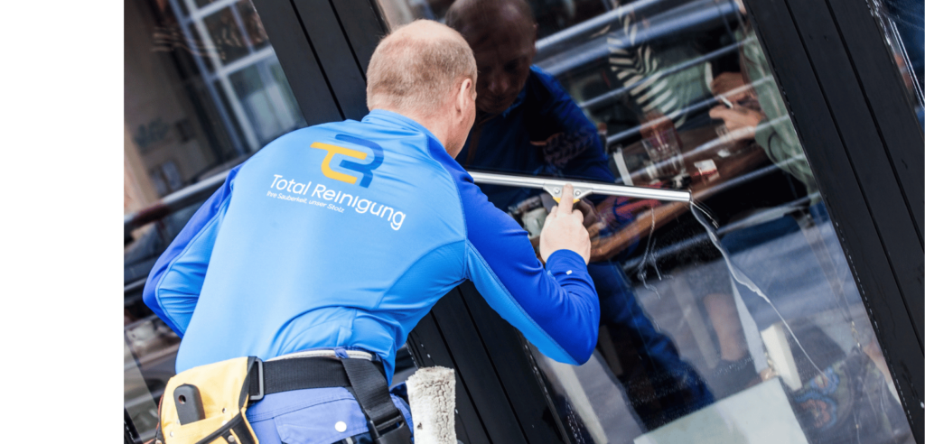 Ein Mitarbeiter von Total Reinigung, der Fenster putzt.
